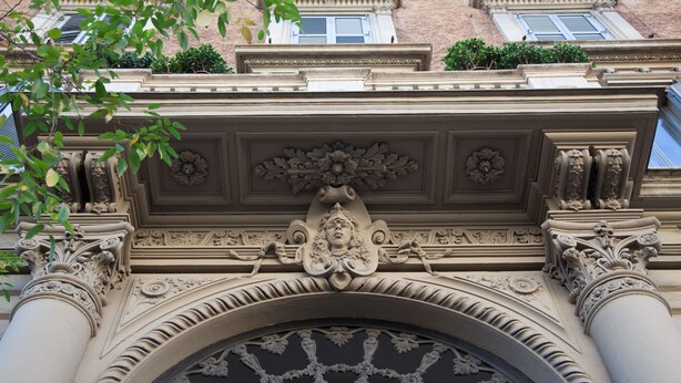 Fachada arquitectónica detallada con esculturas ornamentales y un amplio ventanal de arco.