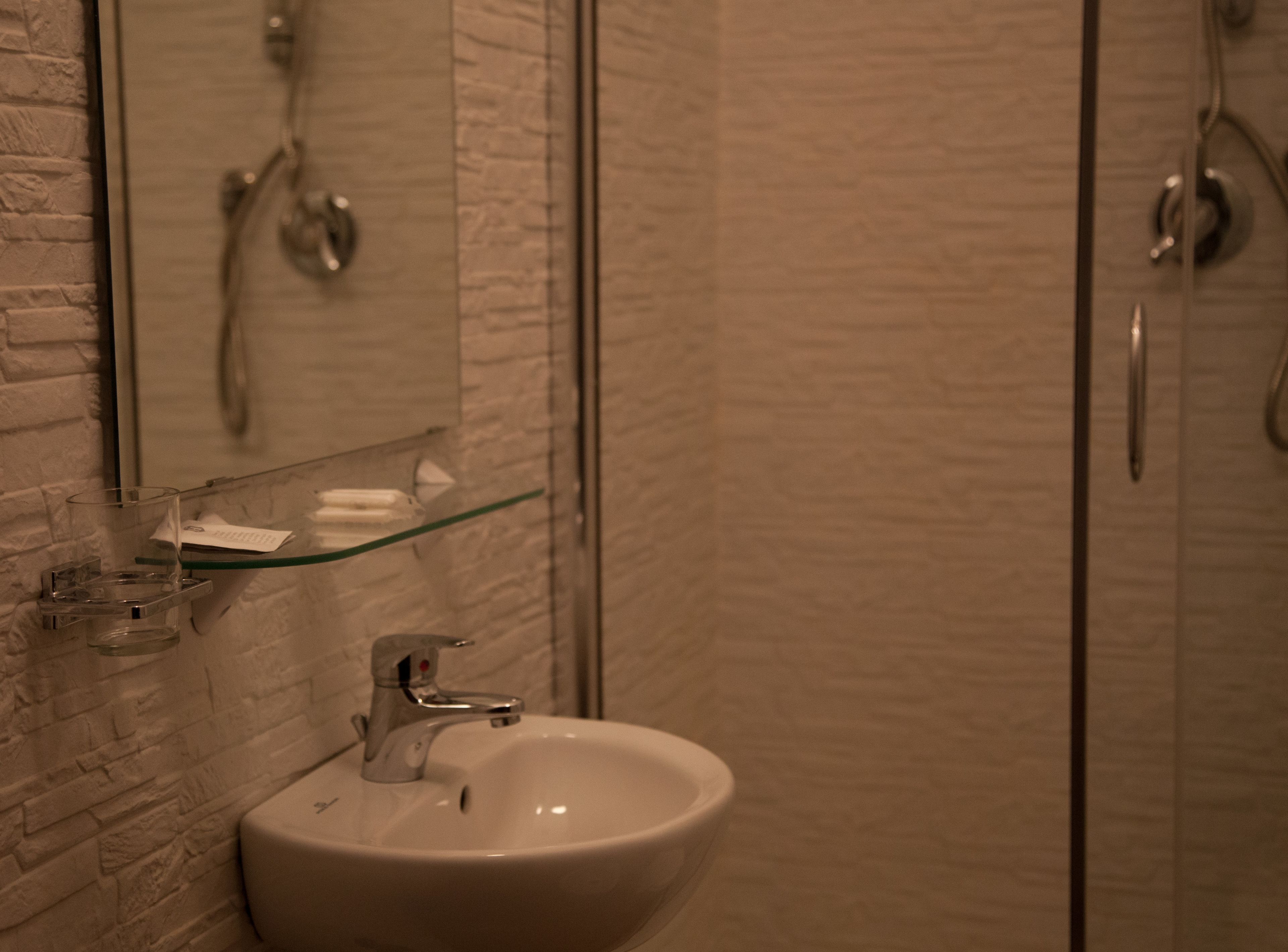 Een badkamer met een witte wastafel, een glazen plank en een spiegel.