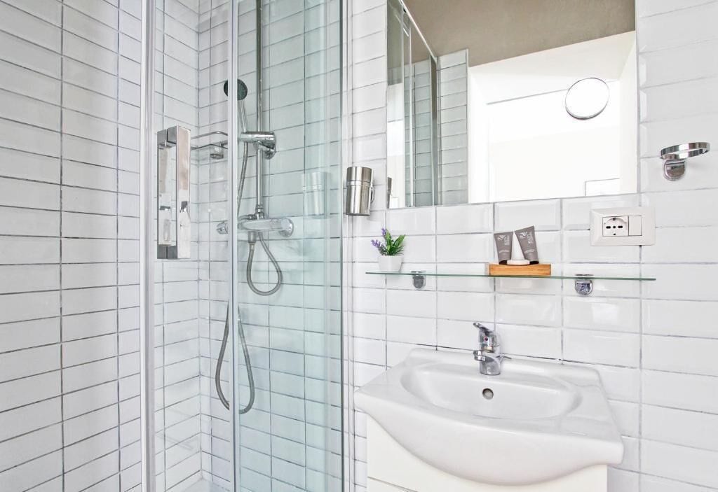 Une salle de bain moderne avec une douche à parois de verre, un lavabo blanc et un miroir au-dessus du lavabo.