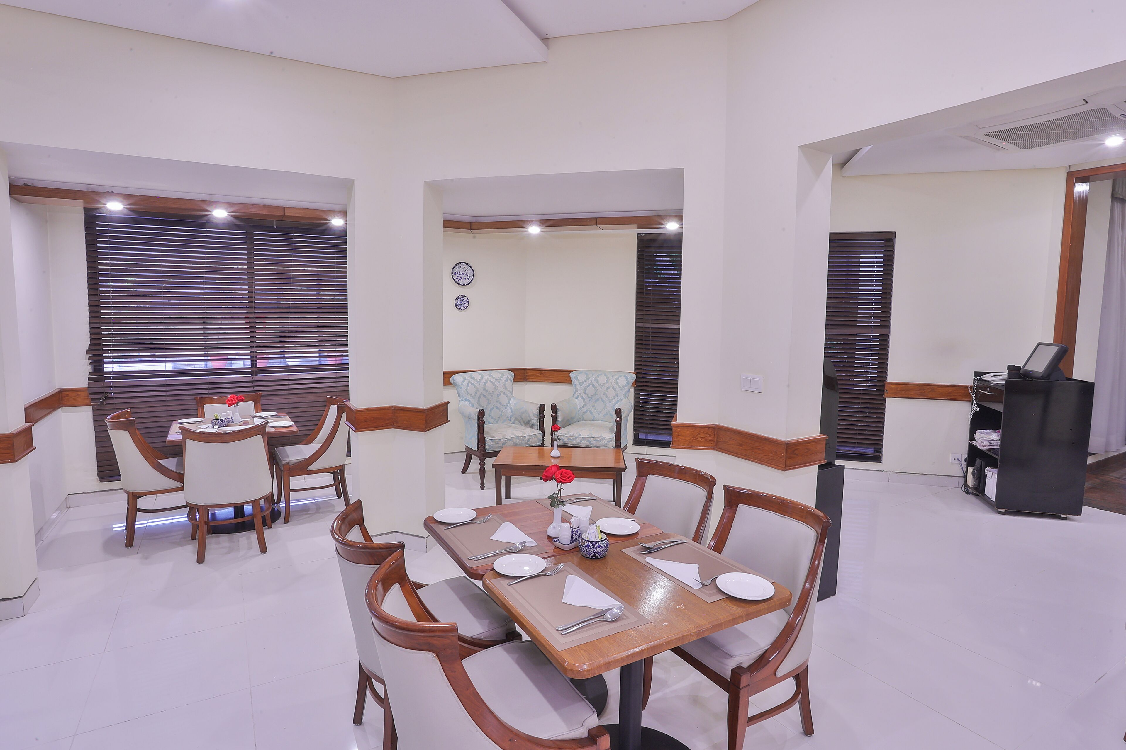 A dining area with a wooden table set for four, surrounded by chairs.