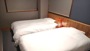A double bed with white linens in a hotel room. - Kokusai Towns Inn (Naha)