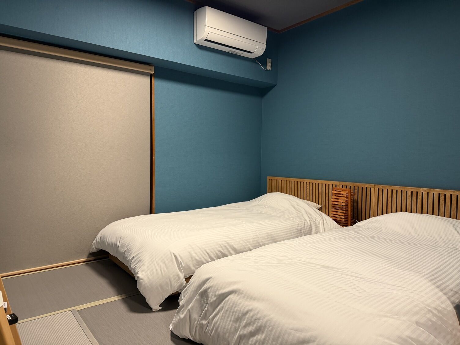 Une chambre avec deux lits, une porte coulissante et un appareil de climatisation.