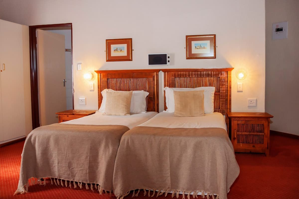 A double bed with a wooden headboard, two bedside tables, and two wall-mounted lamps.