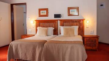 A double bed with a wooden headboard, two bedside tables, and two wall-mounted lamps.