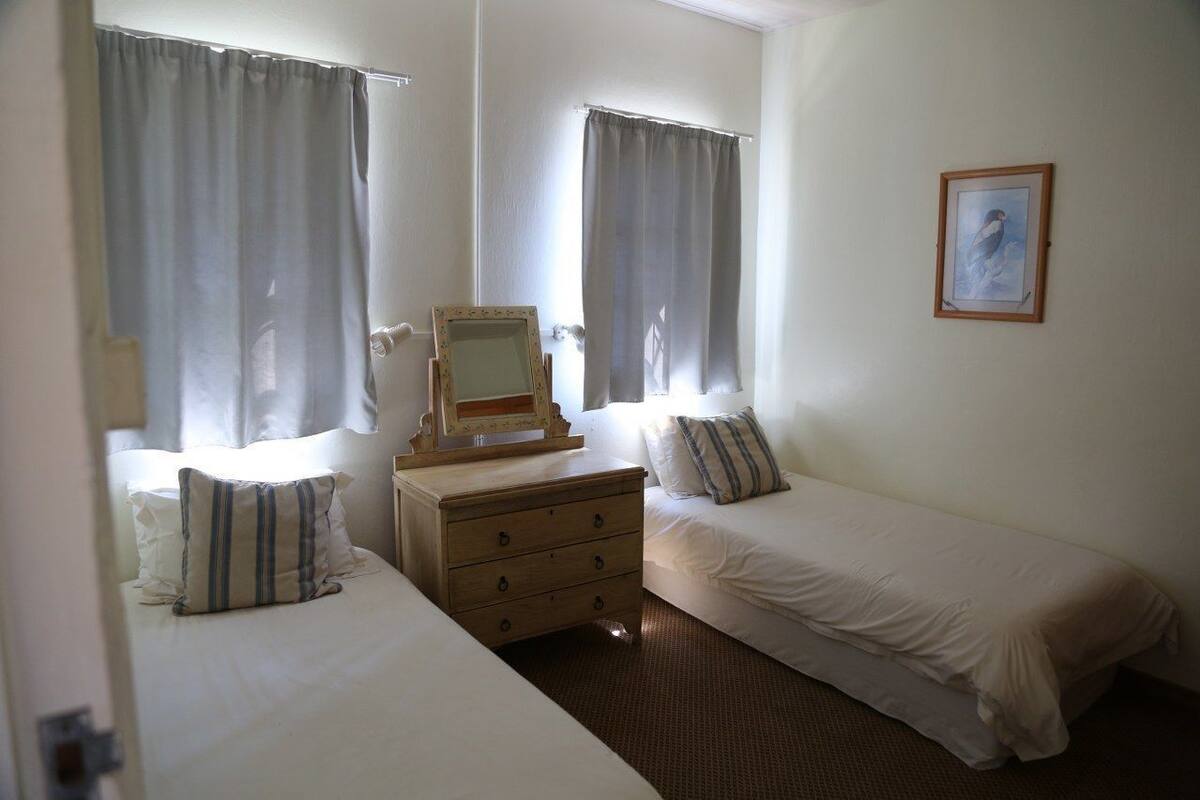 A room with two single beds, a wooden dresser, a mirror, and a framed picture on the wall.