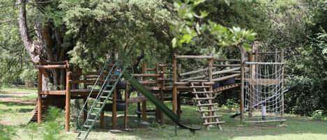 A playground with wooden structures, including a slide and climbing net.