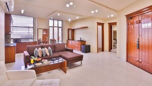 Een ruime woonkamer met een bank, salontafel en een keuken op de achtergrond.