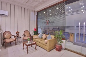 A hotel lobby with a sofa, chairs, a small table, and a potted plant.