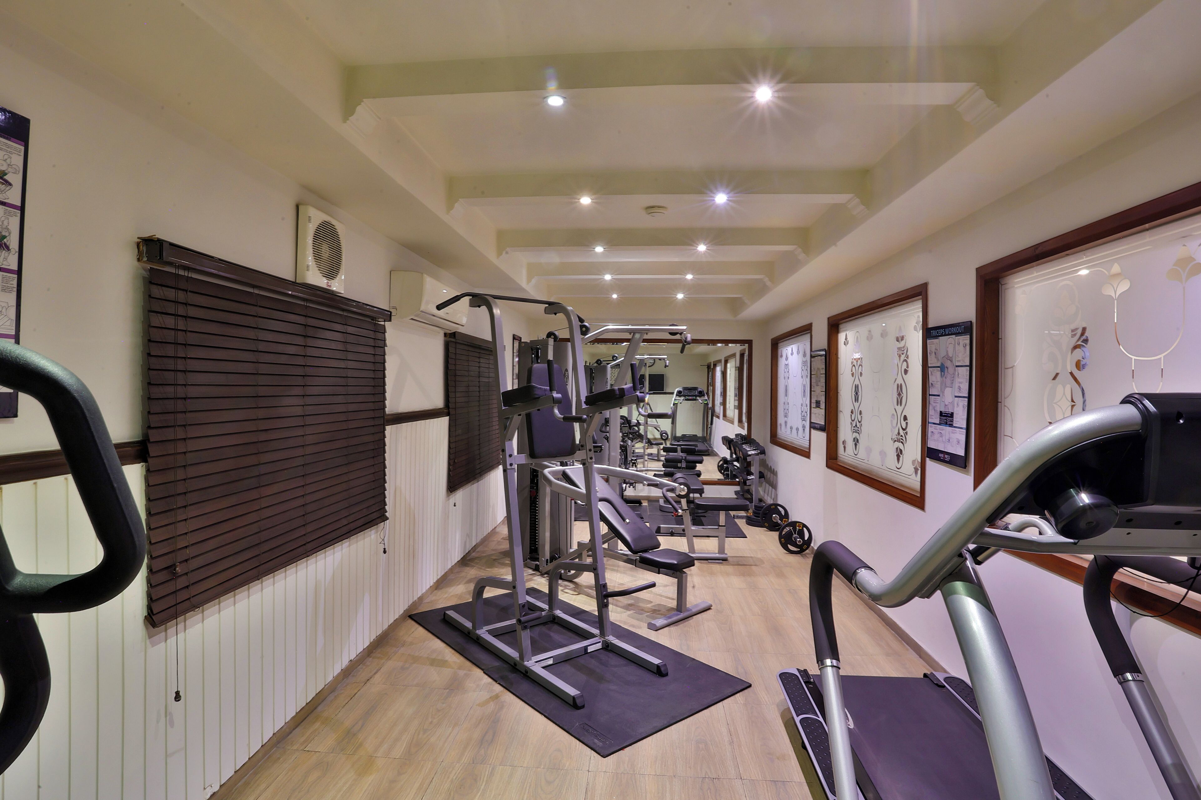 A gym with exercise equipment, wooden floors, and ceiling lights.