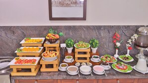 Een buffet met diverse gerechten en drankjes, een inlijsting met een foto aan de muur en een marmeren aanrechtblad.