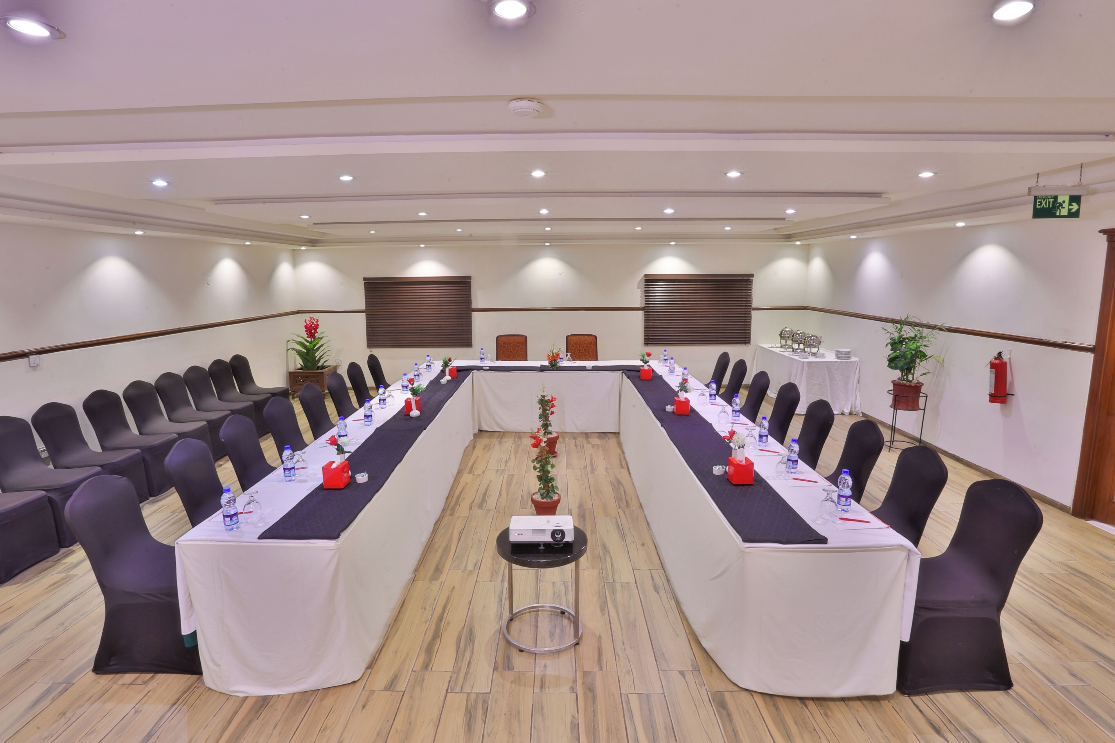 A conference room with a long table, chairs, a projector, and potted plants.