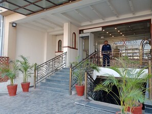 A hotel entrance with a staircase, potted plants, and a sign for 'AVARIX PRESS Hotels & Residences'.