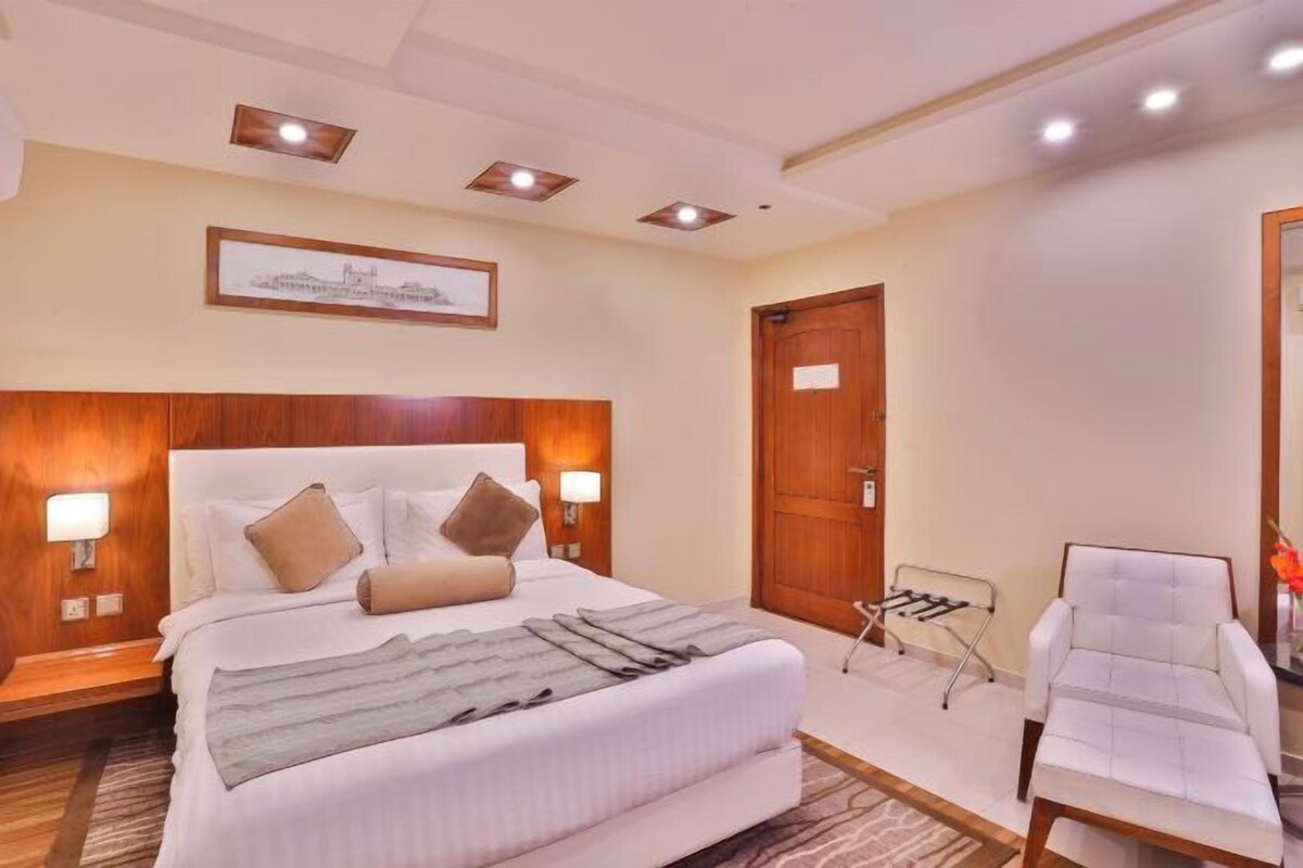 A hotel room with a large bed, bedside lamps, a chair, and a desk.