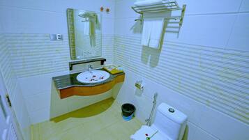 Un baño con lavamanos, espejo, inodoro y toallero.