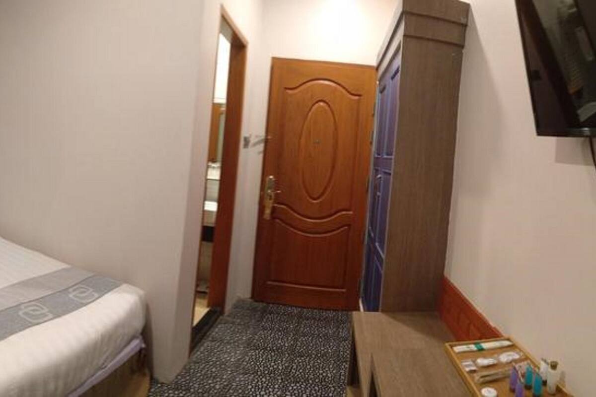 Una habitación de hotel con una cama, una mesita de noche, un televisor y una puerta que da a otra habitación.
