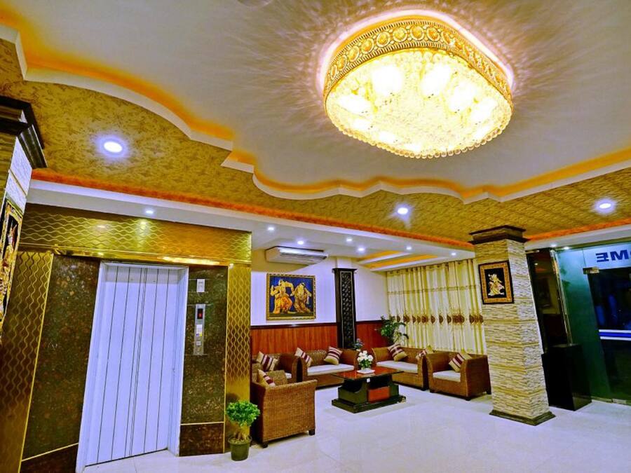 A lobby with a chandelier, sofas, a reception desk, and a wall with a painting.
