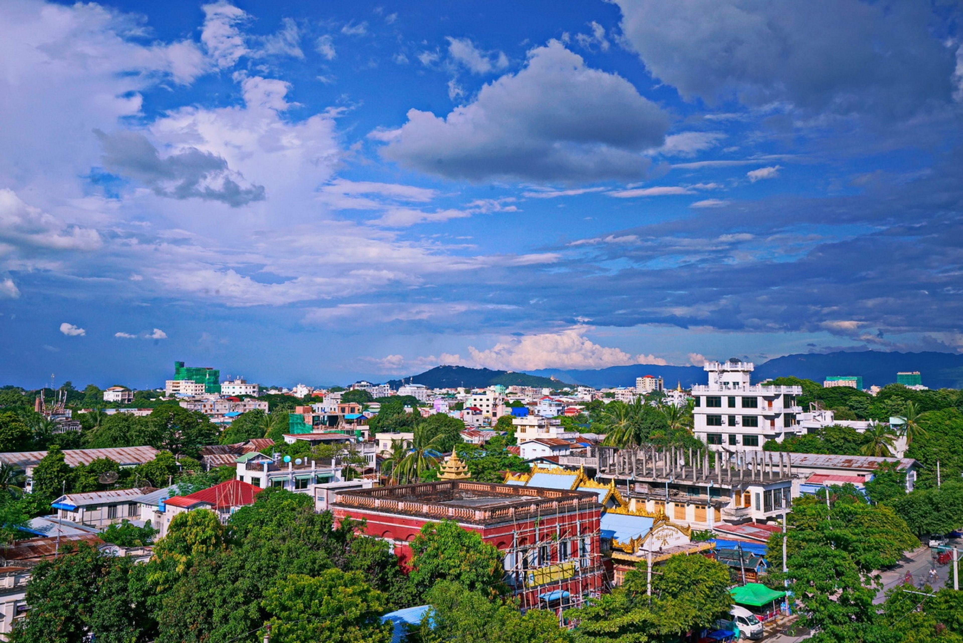 A cityscape with a mix of modern and traditional buildings, including a prominent temple with a golden spire.