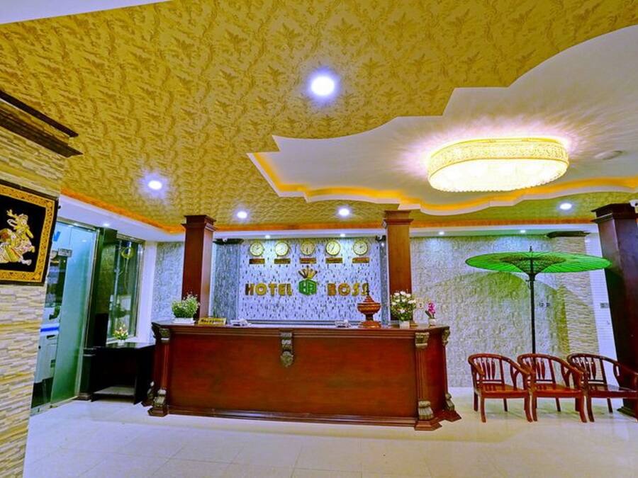 A hotel reception area with a wooden reception desk, a chandelier, and a green umbrella.