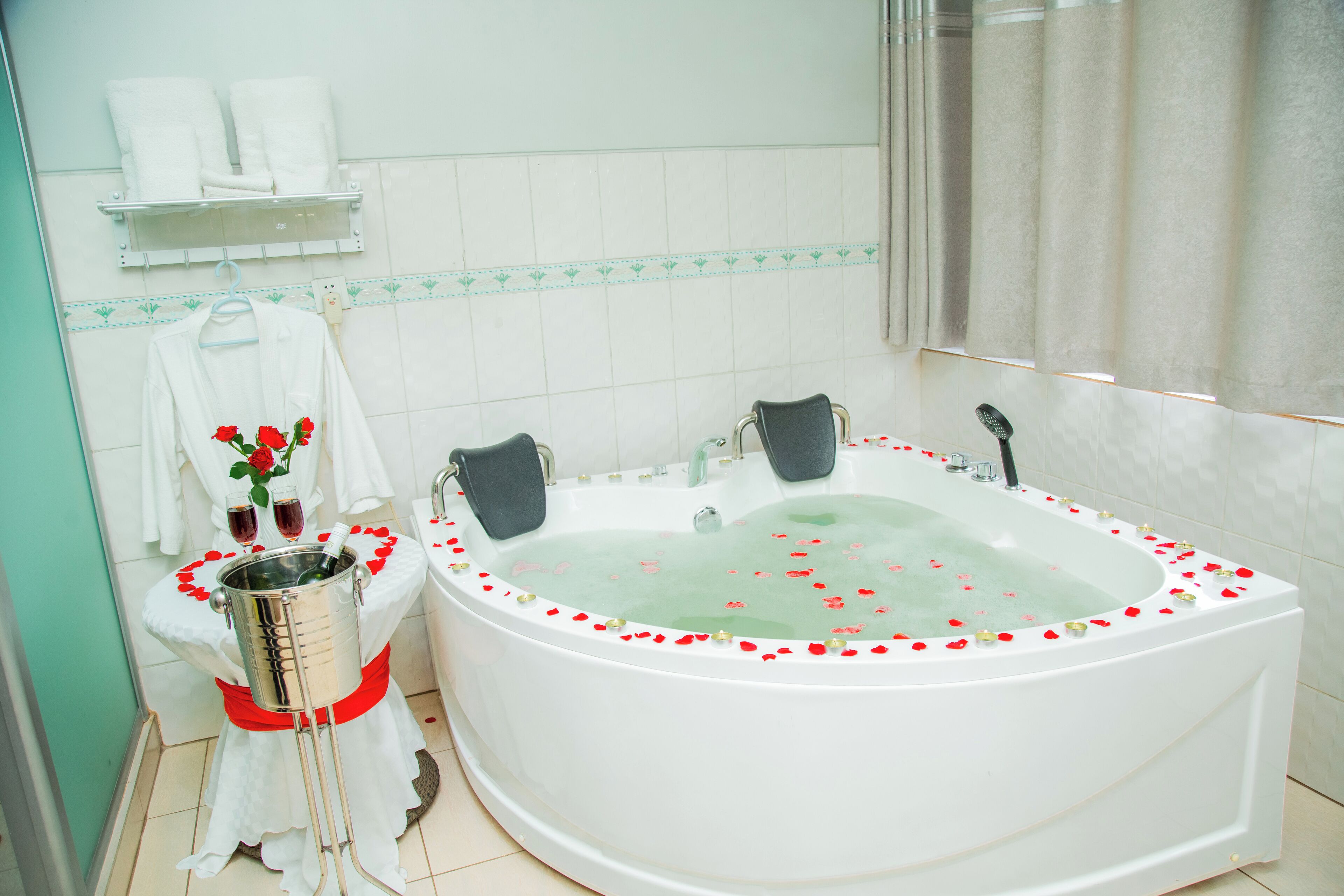 A bathroom with a large bathtub, a shower, and a toilet. There are towels and a vase with flowers on the counter.