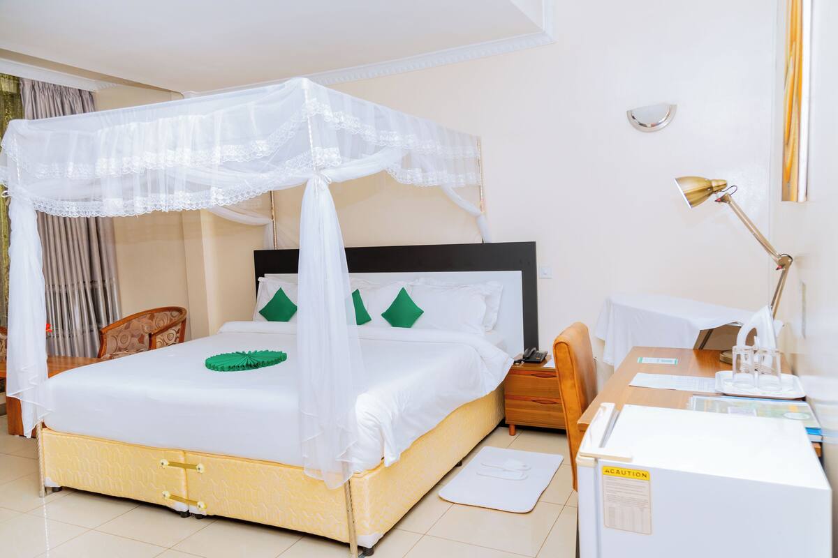 Habitación de hotel ordenada con cama, escritorio, silla y mesita de noche.