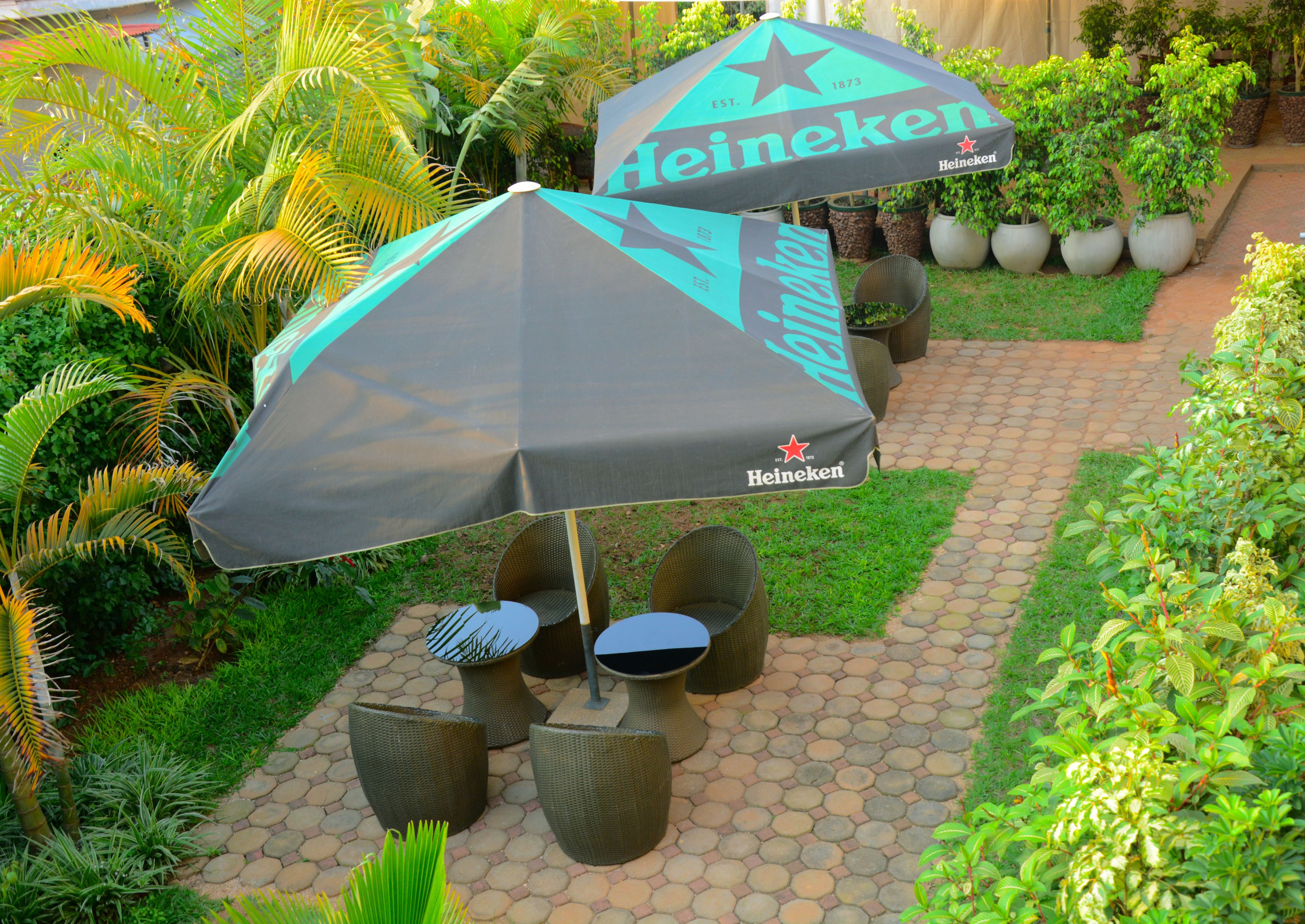 Een terras met Heineken-merk parasols, rieten stoelen en potplanten.