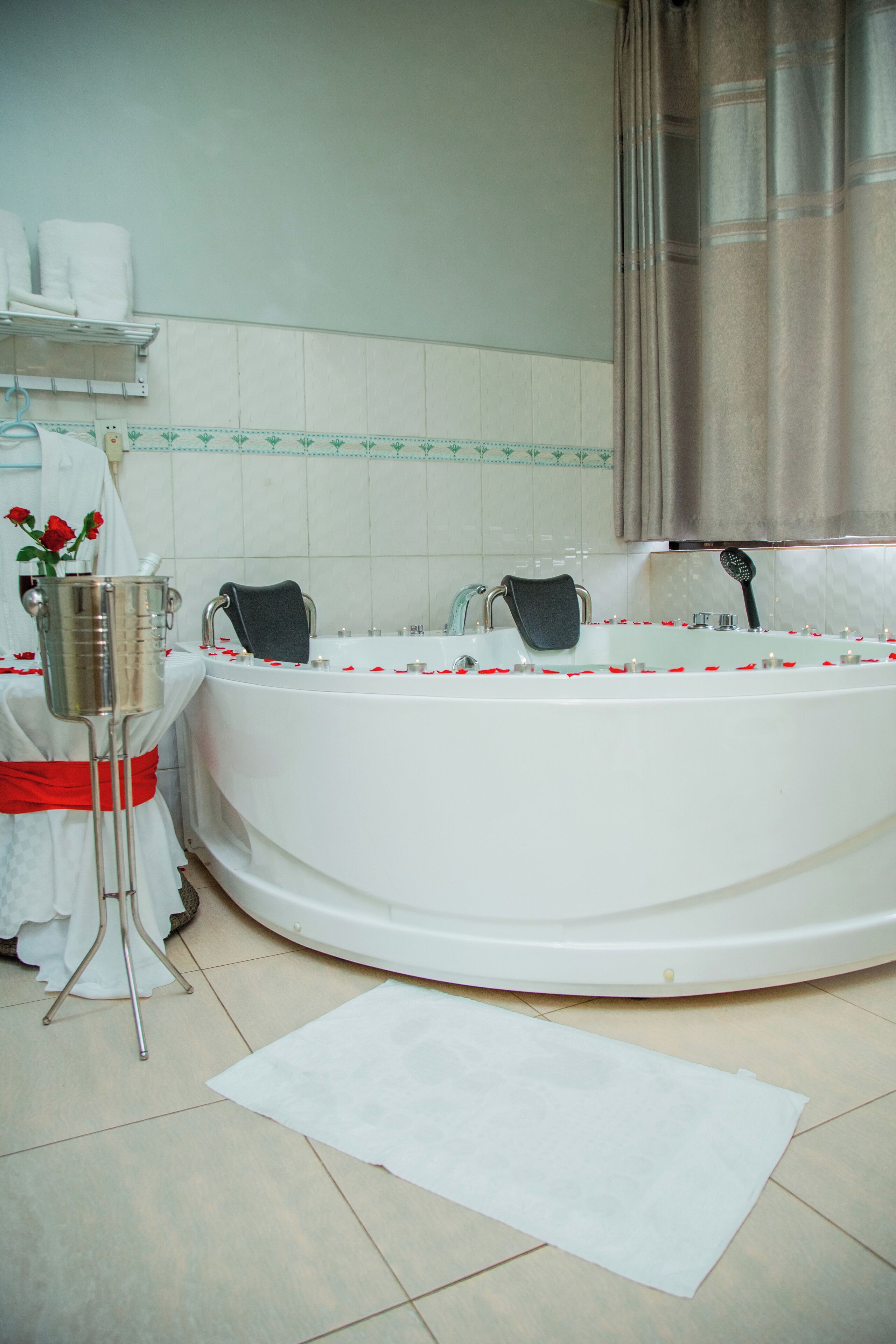 A bathroom with a large bathtub, a vanity with a mirror, and a towel rack.