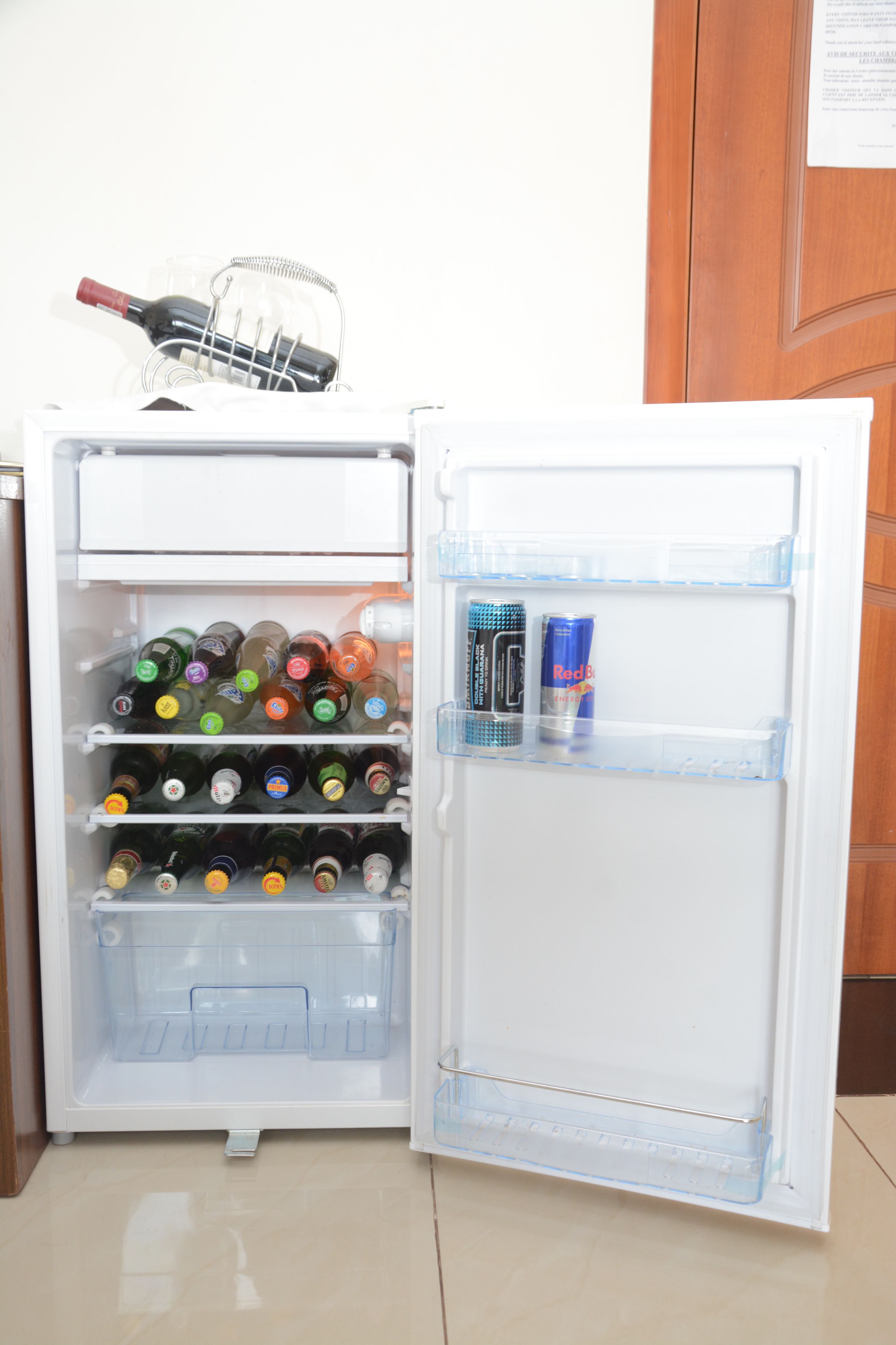 An open refrigerator with shelves stocked with various beverages and a wine bottle.