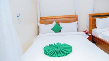 A neatly made bed with white linens, a green decorative pillow, and a wooden headboard.