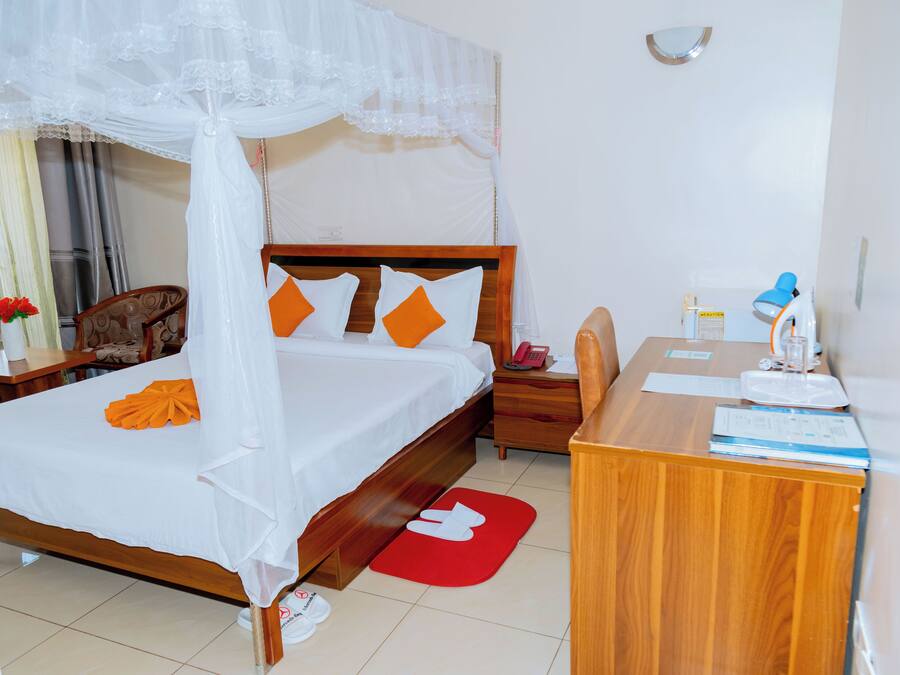 Une chambre d’hôtel comprenant un lit, un bureau en bois, une chaise, une table de chevet et une petite table.