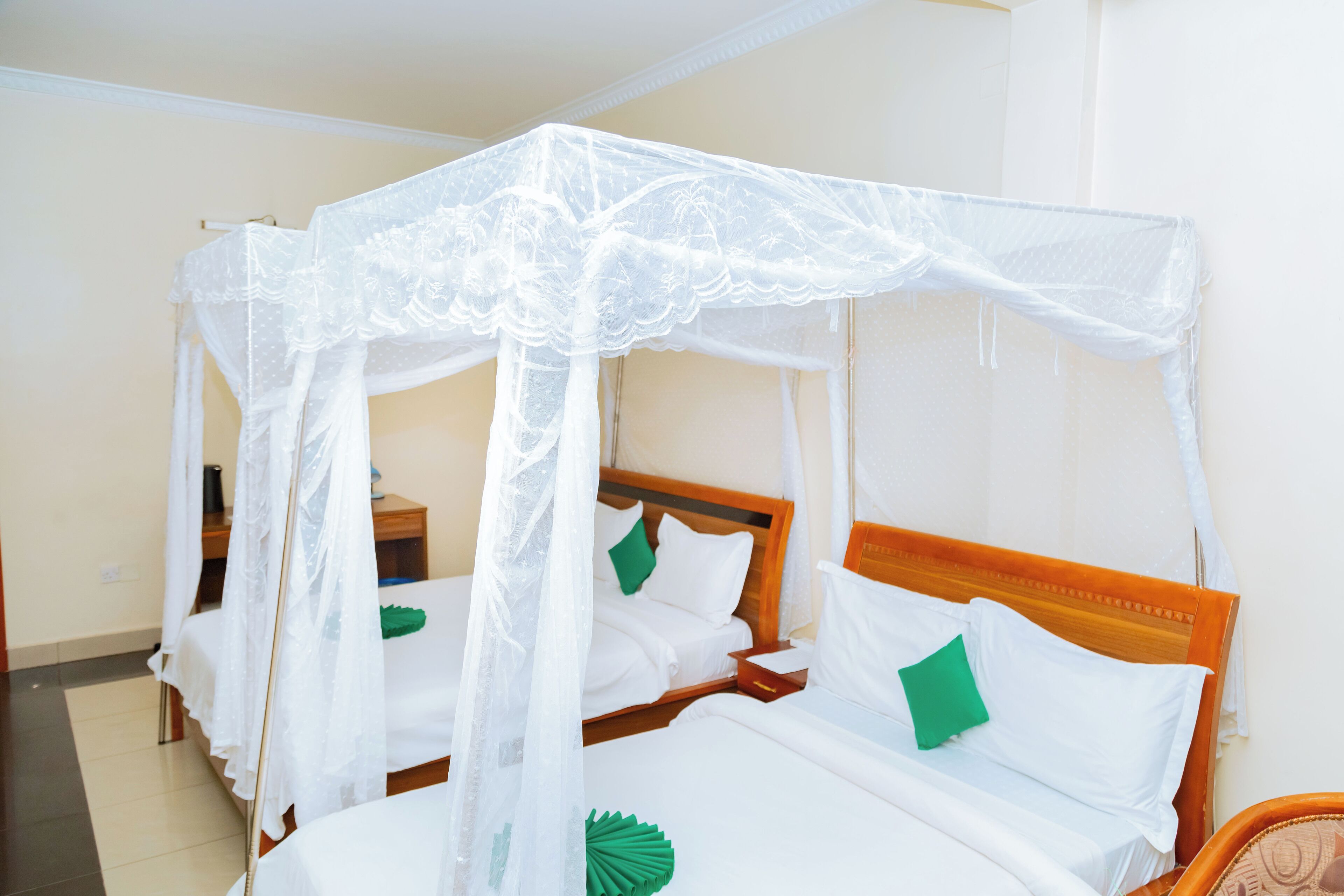 A room with a four-bed setup, each bed with a canopy.