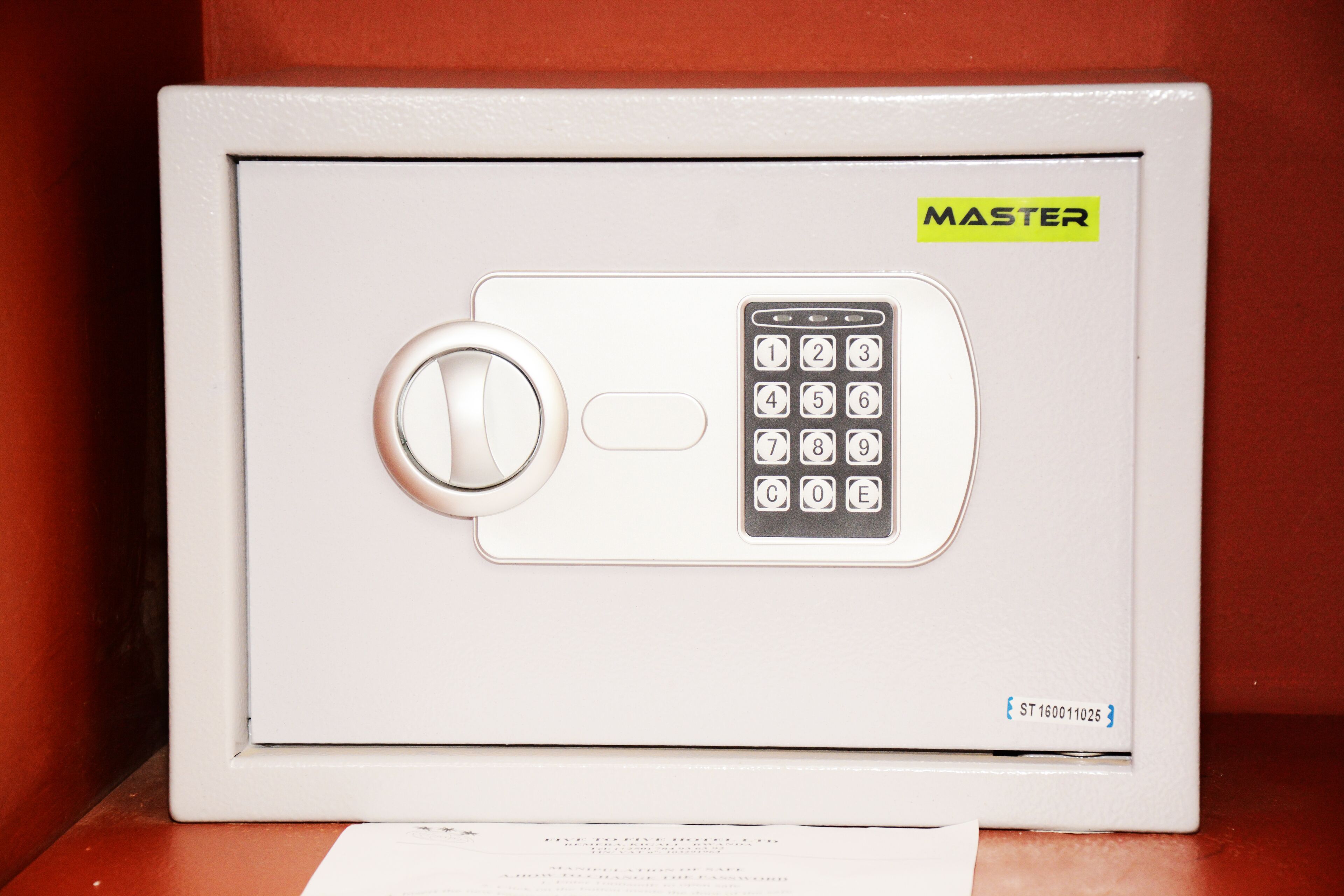 Una caja fuerte blanca con teclado y mecanismo de cierre circular, etiquetada como "MASTER".