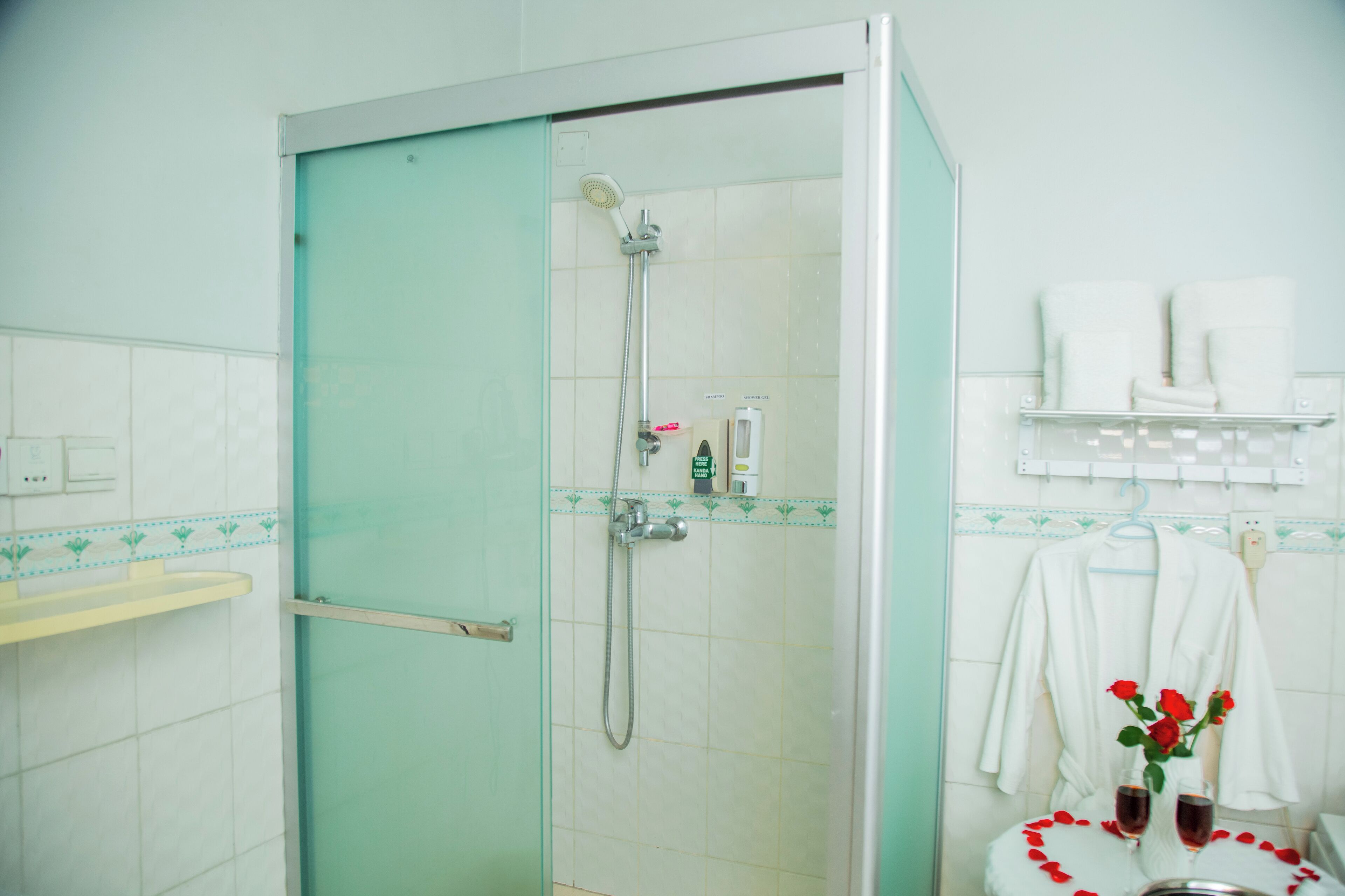 A bathroom with a glass-enclosed shower, a sink with a yellow countertop, and a towel rack with a white robe.
