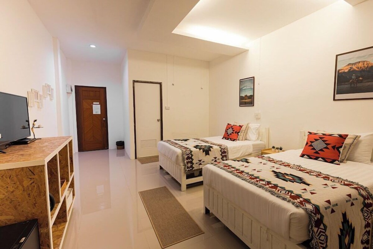 A modern hotel room with two beds, a TV, and artwork on the walls.