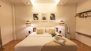 A neatly arranged bedroom with a large bed, two bedside lamps, and three framed leaf artworks on the wall. - 60s Town (Hua Hin)