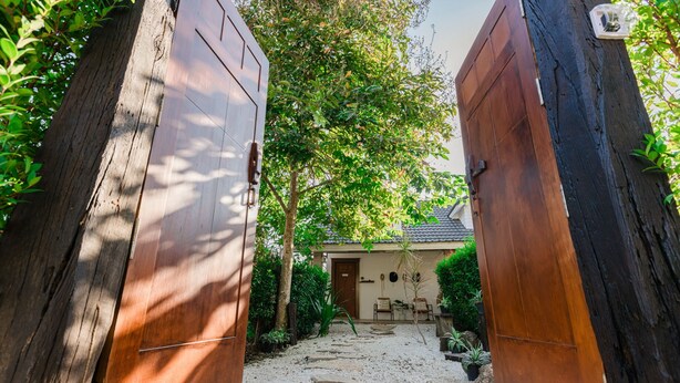 A pathway leading to a house with a traditional design, surrounded by greenery and a gravel path. - 60s Town (Hua Hin)