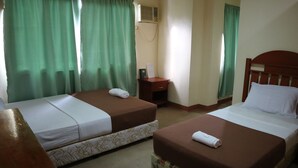A hotel room with two beds, a wooden nightstand, a small table, and green curtains. - Coral Dive Resort (Catarman)