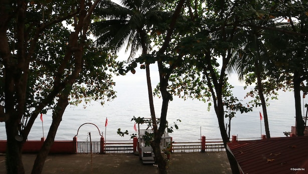A wooden deck with a railing overlooking a calm body of water, surrounded by trees. - Coral Dive Resort (Catarman)