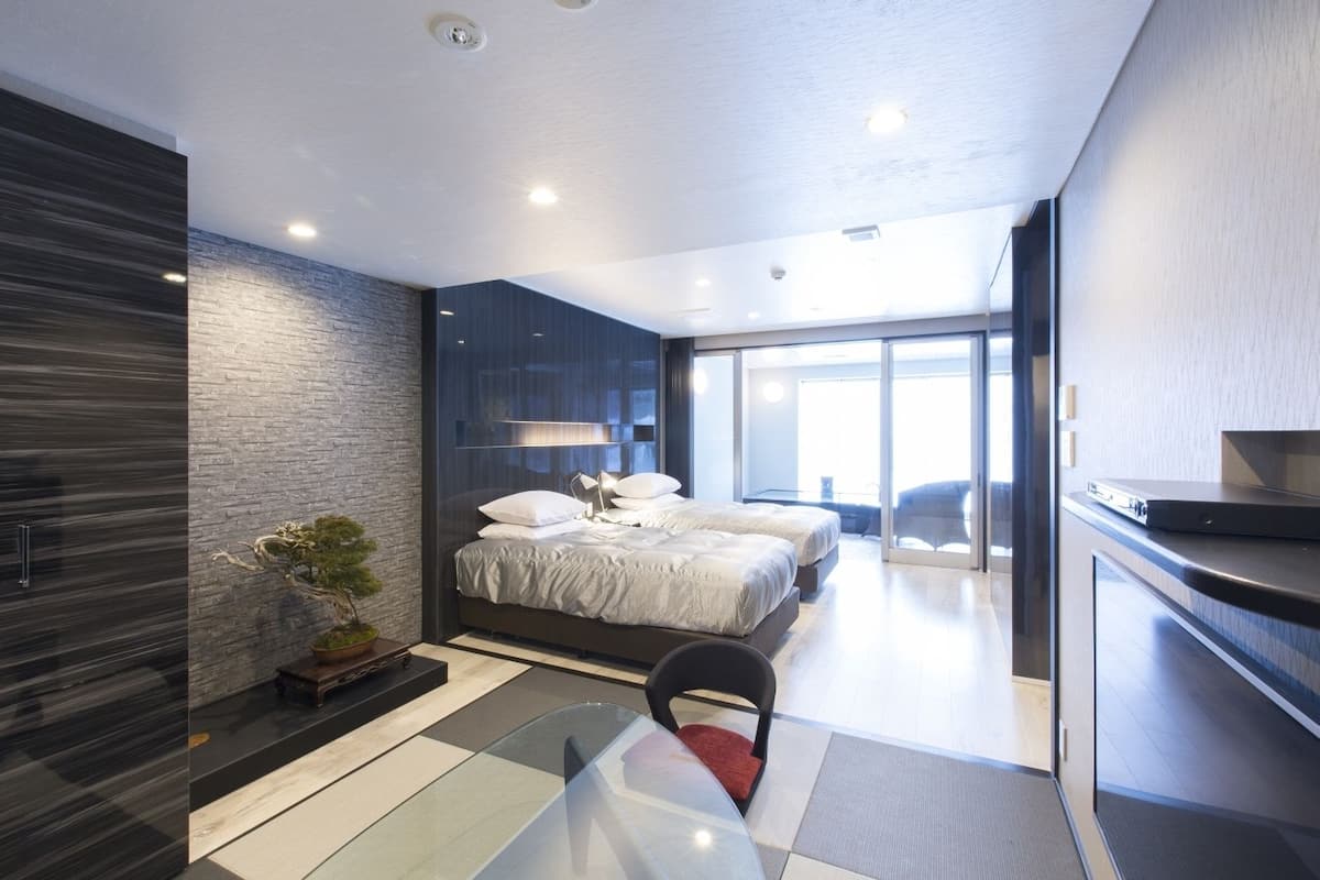 A modern bedroom with a large bed, a glass partition, and a view of the outdoors.