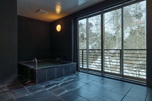 Un baño moderno con un ventanal grande, una bañera y una lámpara redonda.