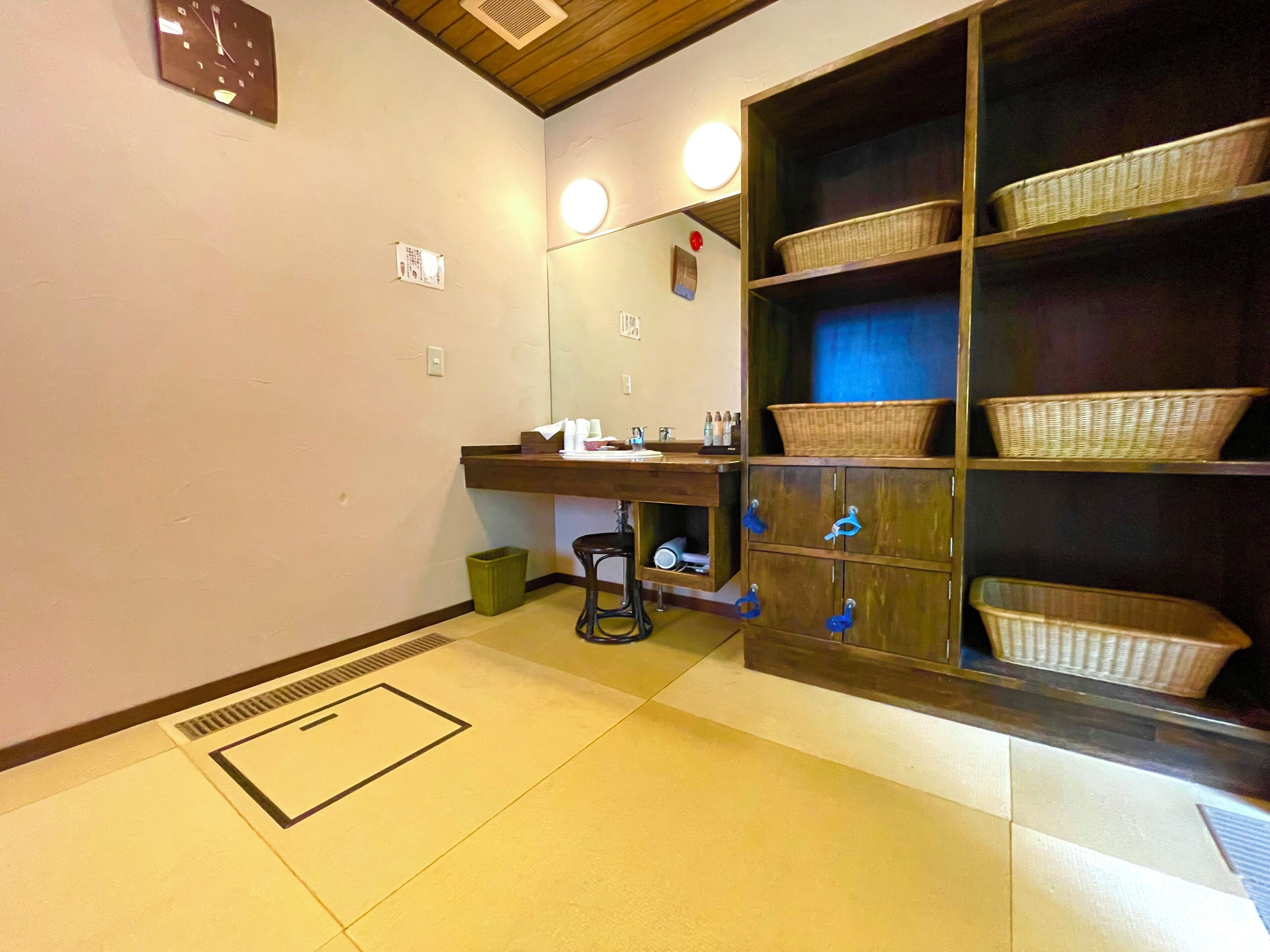 A bathroom with a wooden vanity, a mirror, and wicker baskets on shelves.