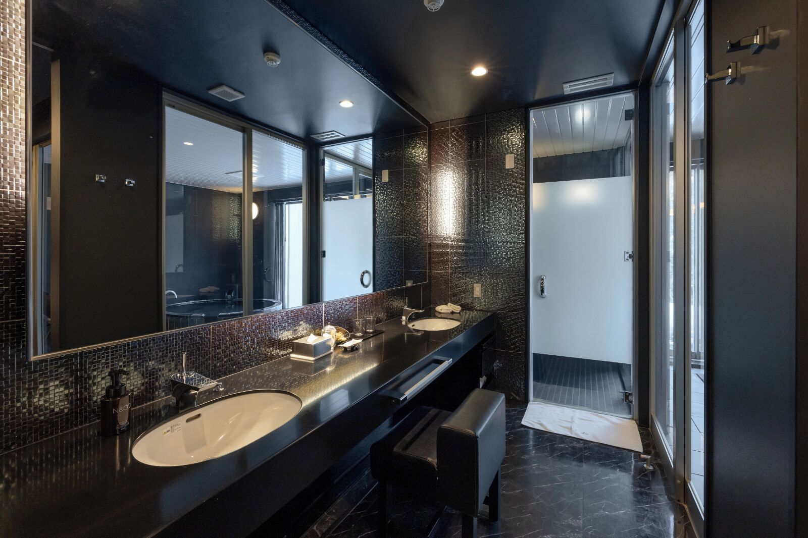 A modern bathroom with two sinks, a large mirror, and a glass shower enclosure.