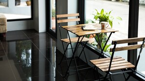 Interior moderno com um banco e mesa de madeira, uma planta em vaso e vista para a rua.