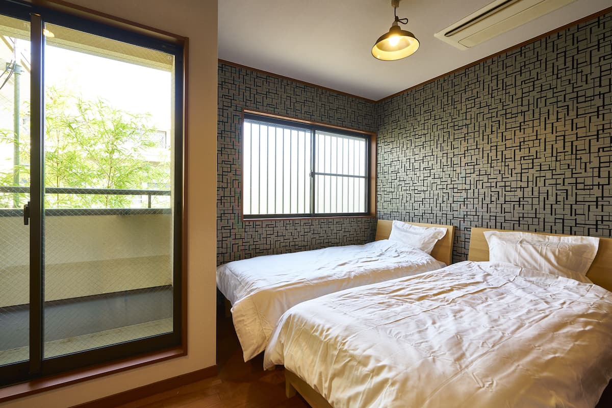 A hotel room with two beds, a large window with blinds, and a patterned wall.