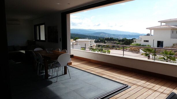 A modern living room with a large window overlooking a scenic view of mountains and a cityscape.