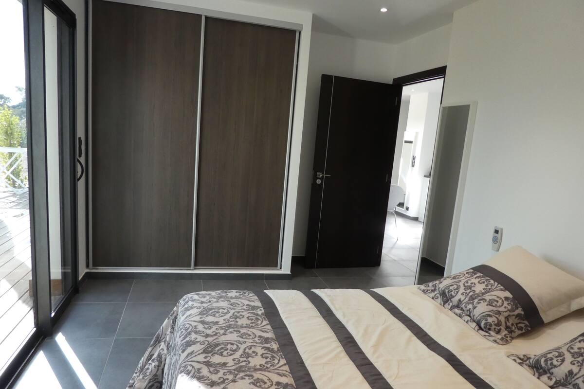 Een slaapkamer met een grote schuifdeur, een bed met beddengoed met een patroon, en uitzicht op de omgeving.