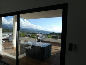 Un balcon doté d’une terrasse en bois, d’une porte vitrée et offrant une vue sur un paysage montagneux.