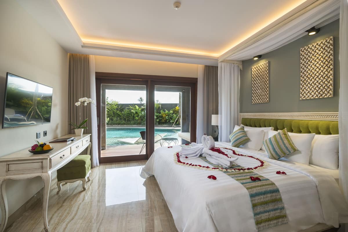 A hotel room with a bed, a desk, a chair, a TV, and a view of a pool.