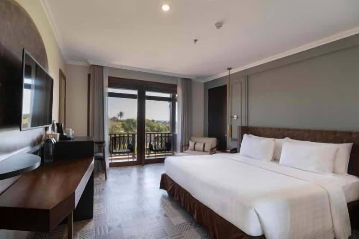 A hotel room with a bed, a desk, a TV, and a balcony with a view.
