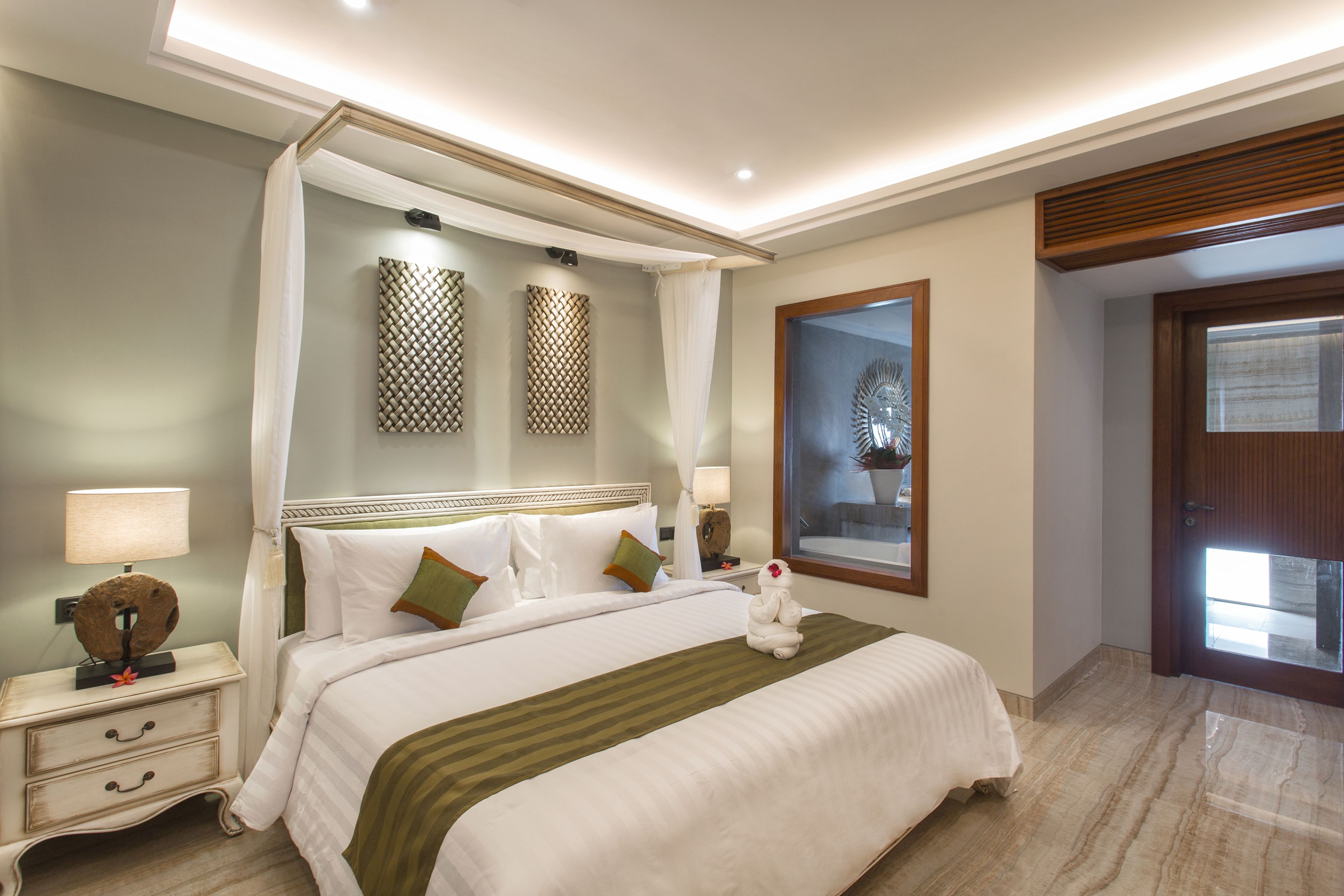 Habitación de hotel con una cama grande, una mesita de noche, una lámpara, un adorno de pared y vistas al exterior.