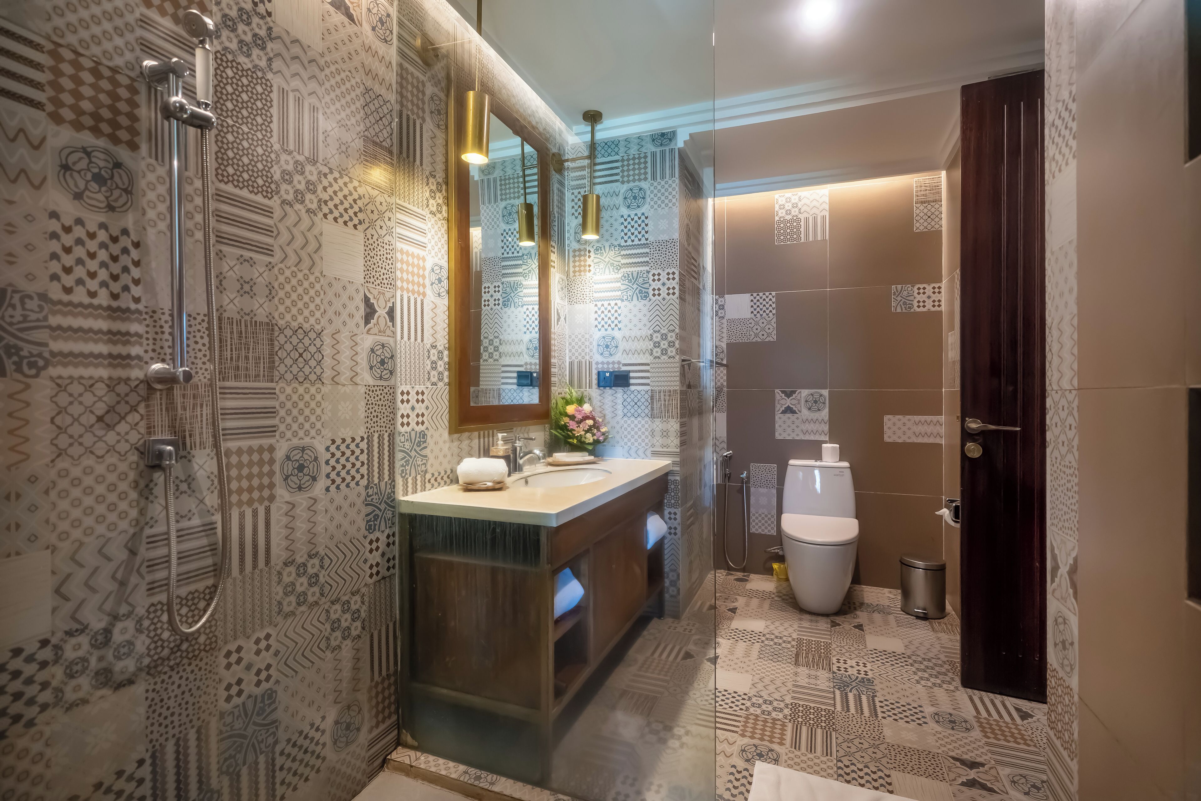 A bathroom with patterned tiles, a sink, a mirror, and a shower.